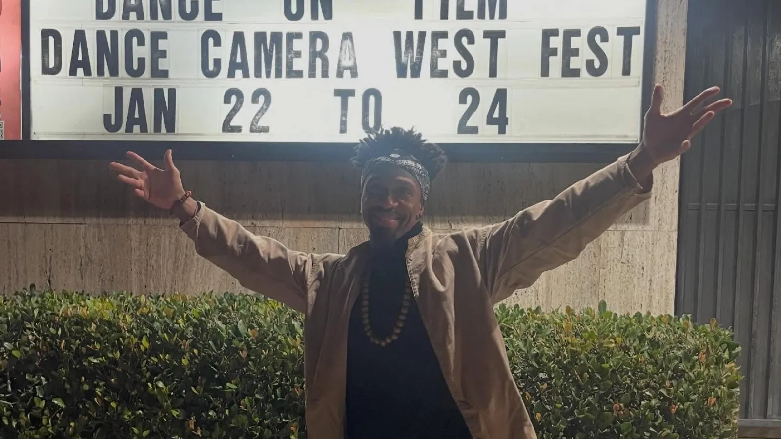 A person raising his arms in front of a sign 
