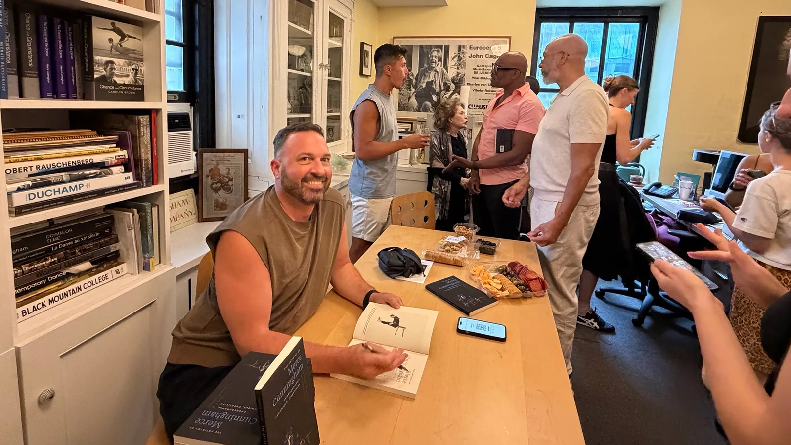 Person signing books at a table with a group of people standing in line