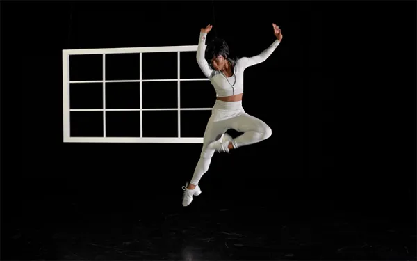 Dancer leaping in front of window frame