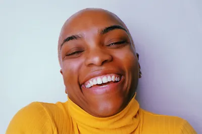 A headshot of a person wearing a yellow sweater