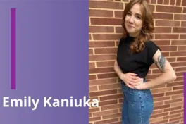 a person with long auburn hair standing in front of brick wall